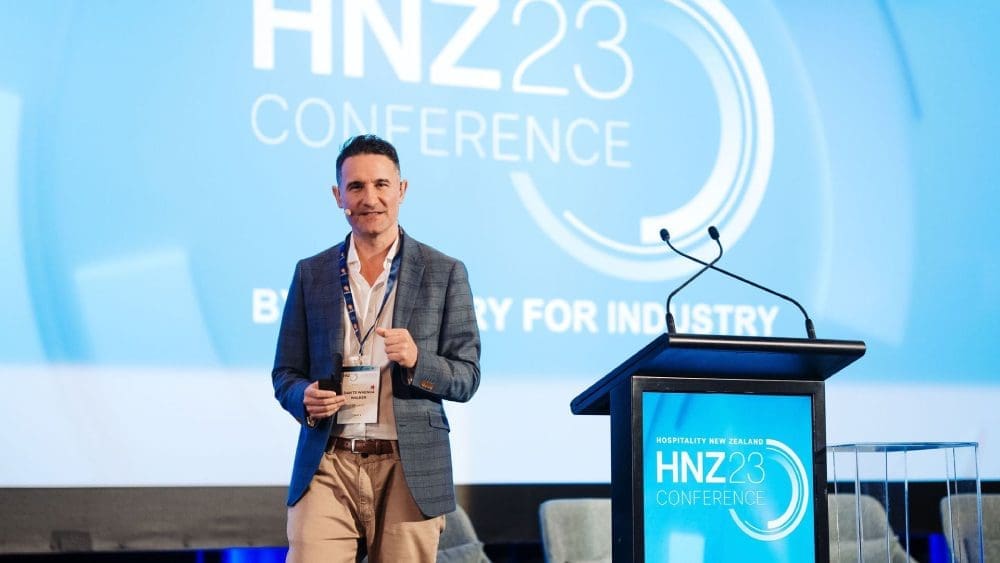 A man standing in front of a microphone at a conference.