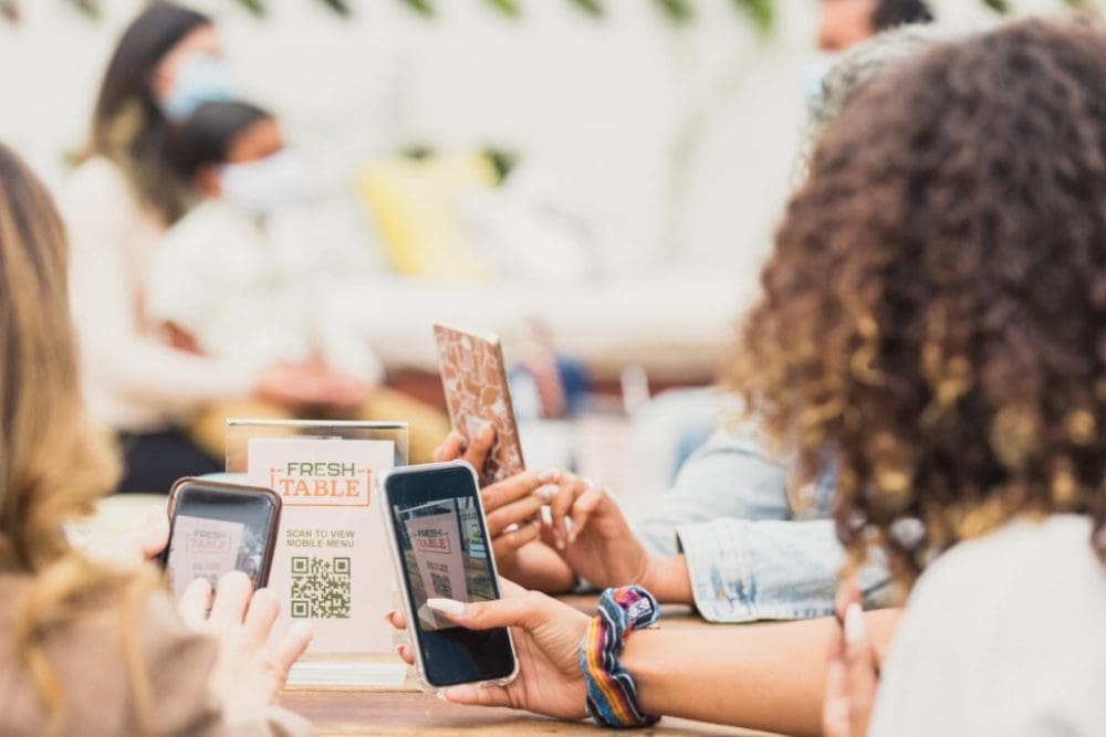 A group of people sitting at tables looking at their phones.